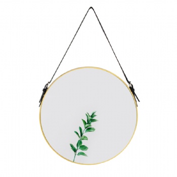 Round mirror with gold frame on the wall