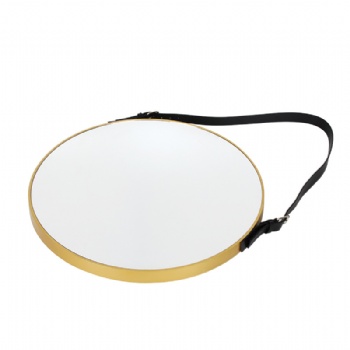 Round mirror with gold frame on the wall